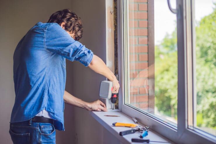 Man in a blue shirt does window installation